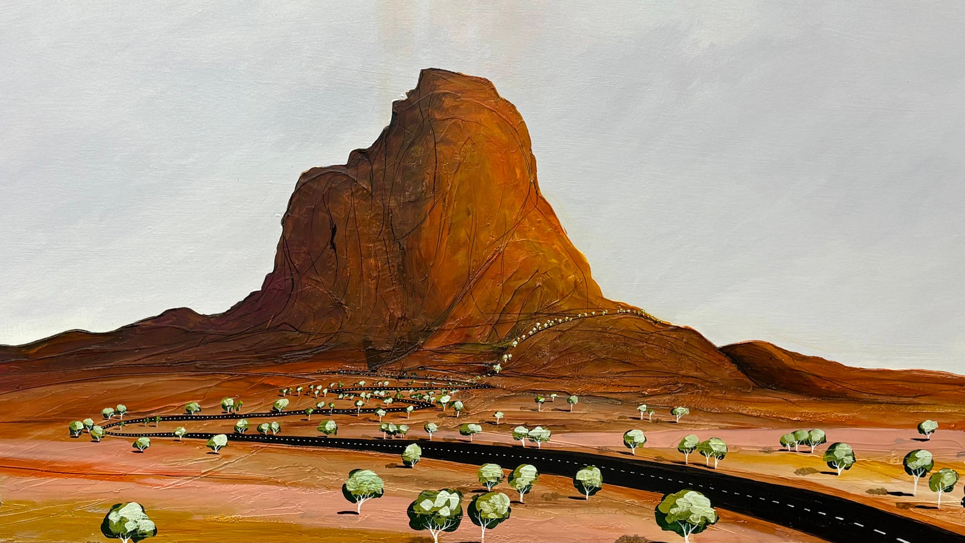 Desert landscape with a large rock formation and sparse trees.