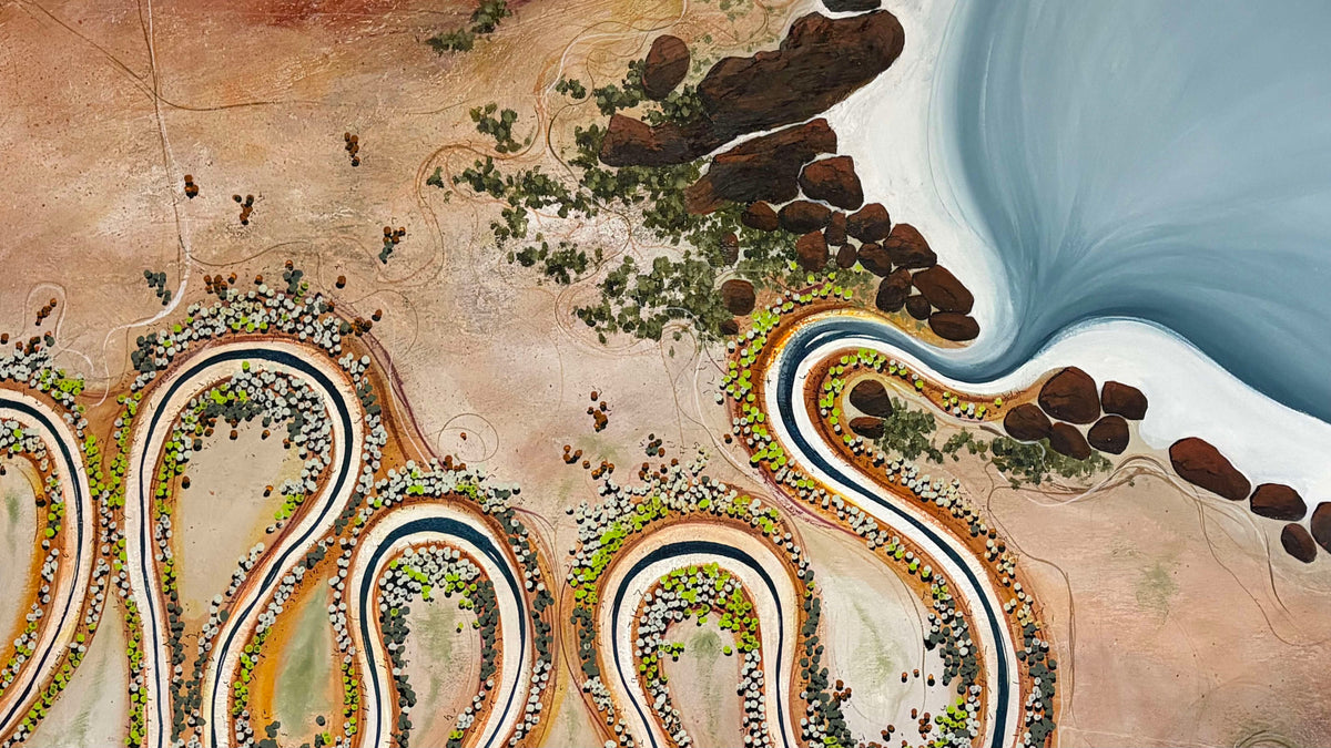 Aerial-style artwork showing a desert landscape with winding roads, clusters of small figures, rocks, and a large blue body of water.