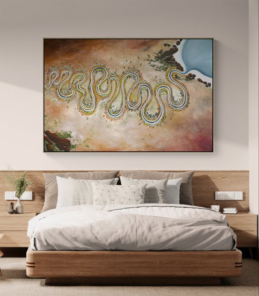 A large framed abstract wall art print depicting a winding river or coastline in beige, brown, blue, and green tones, displayed above a modern wooden bed in a neutral bedroom setting.