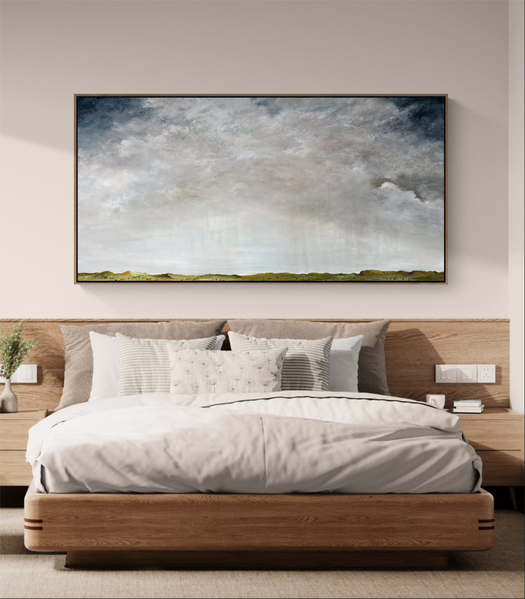 A large framed landscape painting of a cloudy sky and distant green hills, displayed above a modern wooden bed in a neutral-toned bedroom.