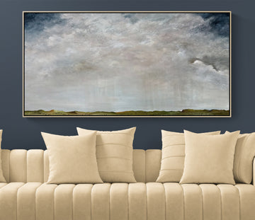 A large framed landscape painting of a cloudy sky hangs on a dark blue wall above a beige tufted sofa with cream pillows.